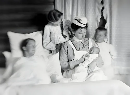 A wet nurse holds a newborn baby ca. 1904